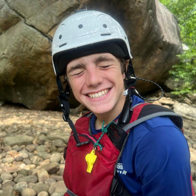 a person wearing a helmet standing next to a rock
