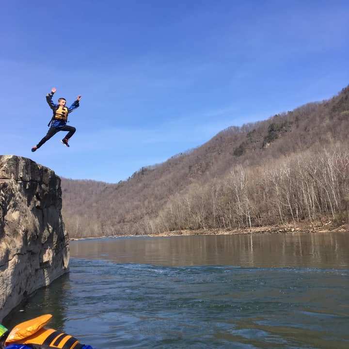 a man flying through the air while riding a motorcycle down a river