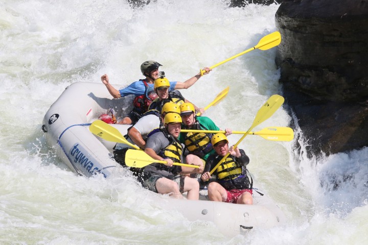 a man riding a wave on a raft in a body of water