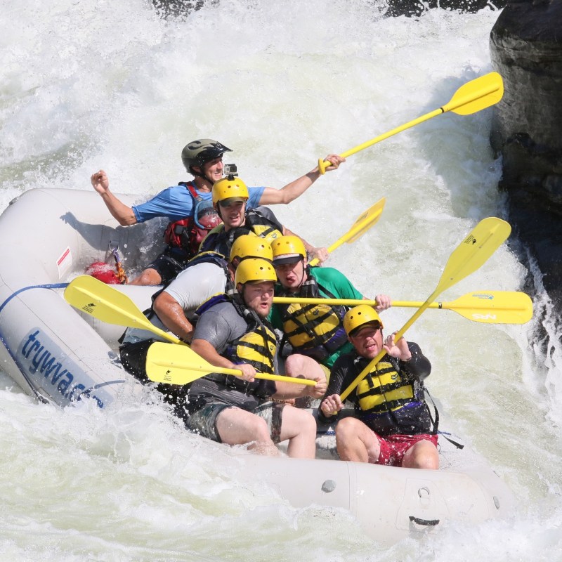a man riding a wave on a raft in a body of water