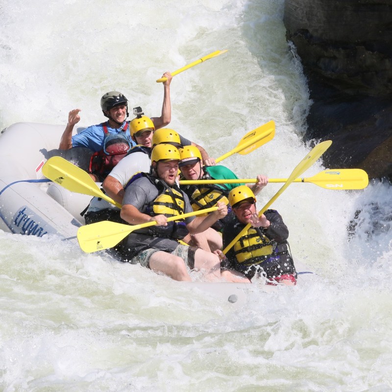 a man riding a wave on a raft in a body of water