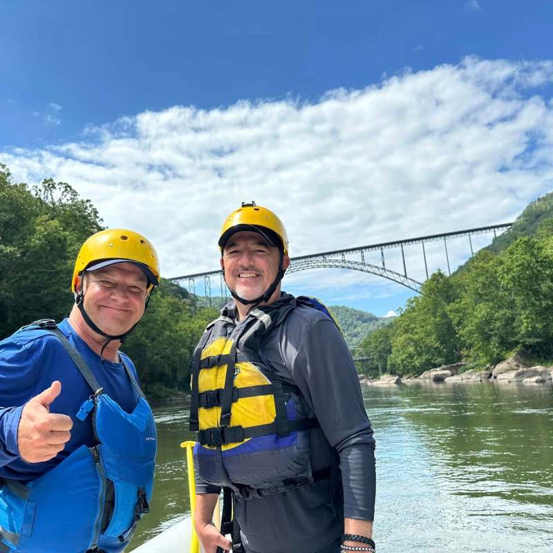 a man holding a pair of people posing for the camera