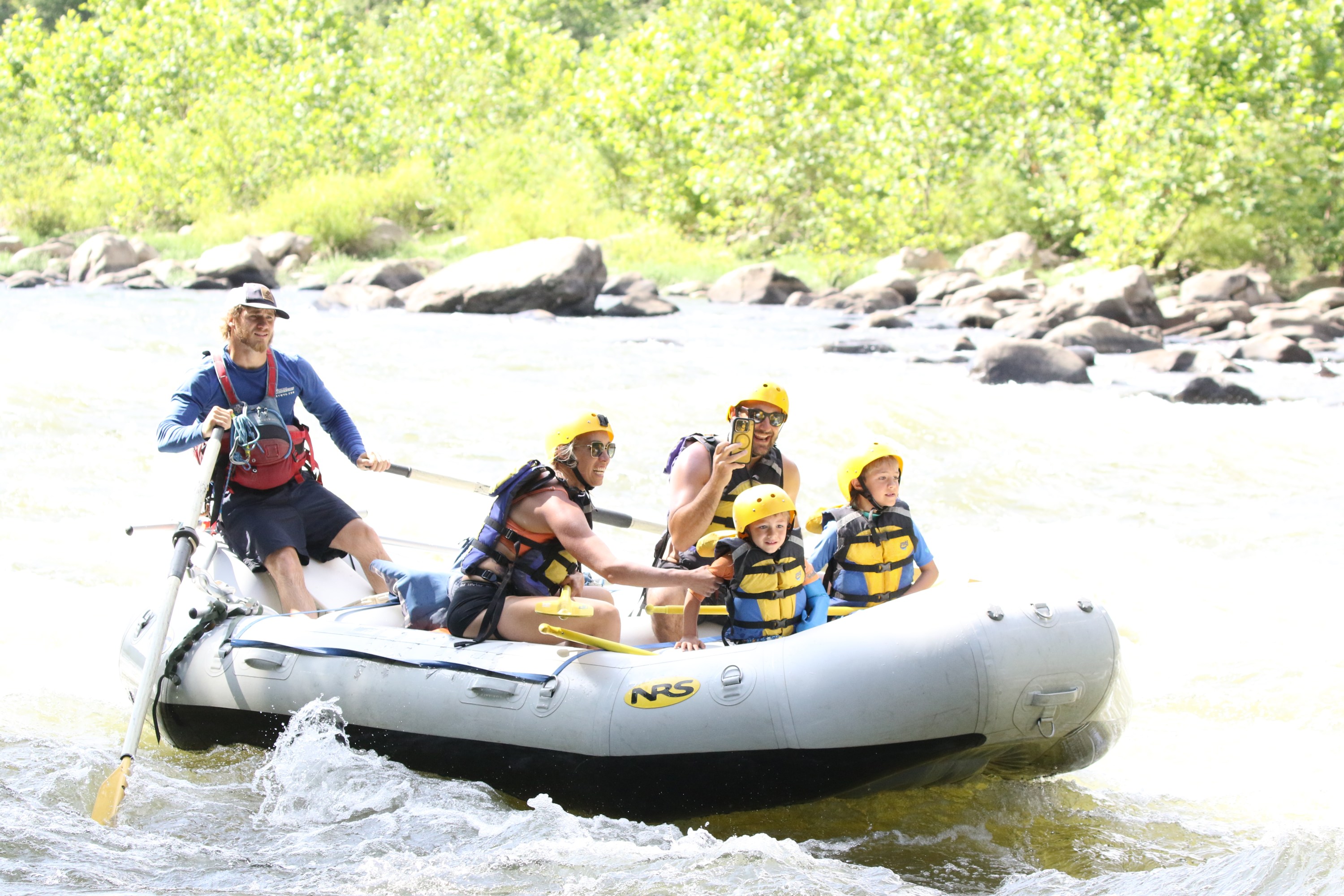 Group of people whitewater rafting on a sunny day.