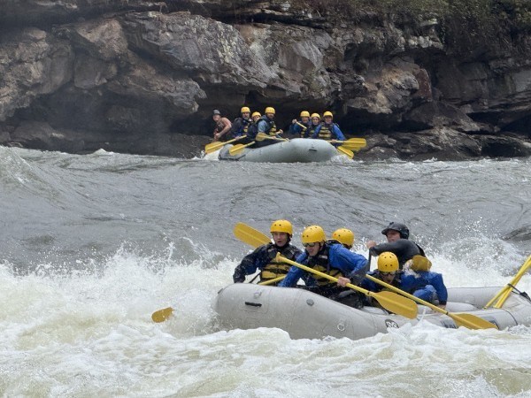 Two groups white-water rafting on a rocky river.