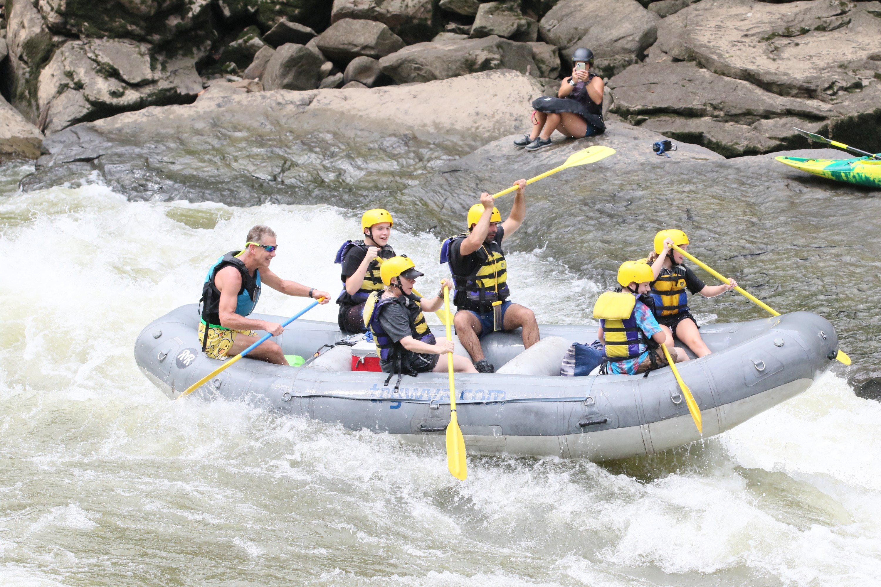 Group in yellow helmets rafting on a river.